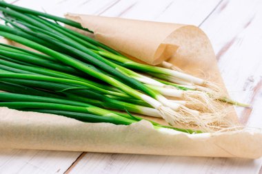 Hafif ahşap zemin üzerinde bir demet yeşil soğan.