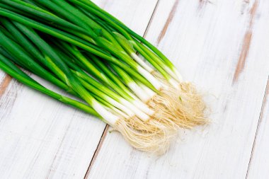 Hafif ahşap zemin üzerinde bir demet yeşil soğan.