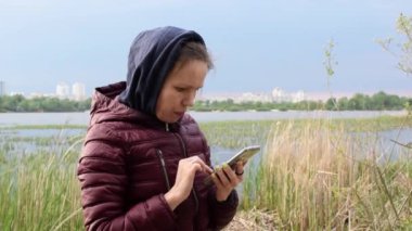 Nehir kenarındaki telefonda yazan bir kadın..