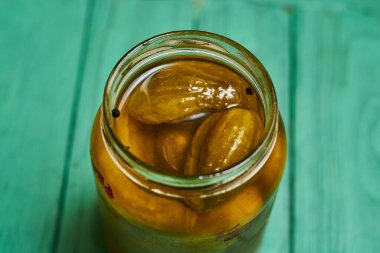 Yeşil arka planda kavanozda salatalık turşusu..