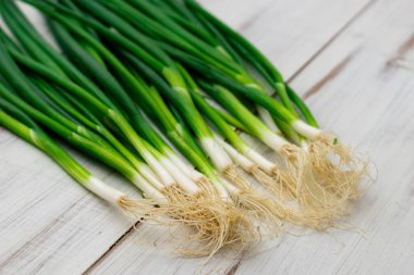 Hafif ahşap zemin üzerinde bir demet yeşil soğan.