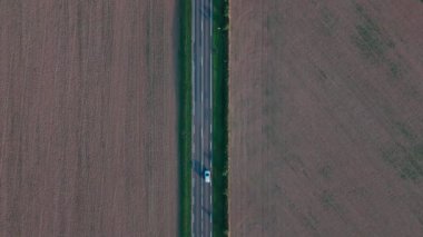 Kırsal yoldaki araçların geniş tarım alanlarından hava görüntüsü.