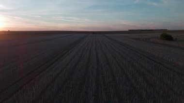 Mevsimsel hasatı vurgulayan geniş tarım tarlaları üzerinde gün batımı.