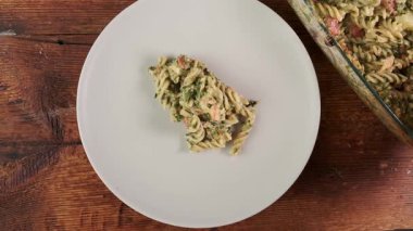 Tahta masadaki ahşap çatal bıçaklı bir tabak pesto makarna hazırlıyorum..