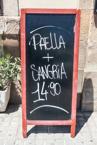 Tafel eines Restaurants in Barcelona, Spanien, das zwei typisch spanische Produkte anbietet: Paella und Sangria. typische sommerliche Speisekarte — Stockfoto