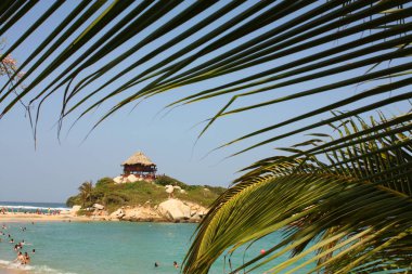 Karayip sahilinde hamamcılar ve tepedeki Kulübe. Tayrona Ulusu