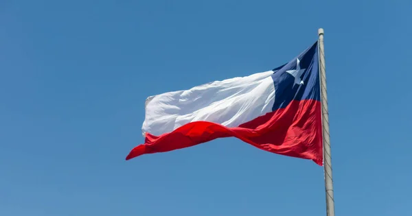 Bandera de Chile ondea en un fuerte viento contra un cielo azul brillante w — Foto de Stock