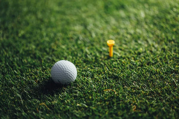 高尔夫球附近黄色三通在绿色草 特写看法 — 图库照片
