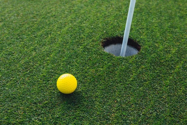 Gul Golfboll Närheten Hål Med Pin Flagga Grönt Gräs Bakgrund — Stockfoto