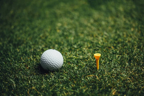 高尔夫球附近黄色三通在绿色草 特写看法 — 图库照片