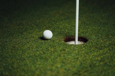 Golf topu yakın PIN bayrak, yeşil çim arka plan, closeup görünümü ile delik