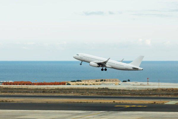 отправление белого реактивного самолета, взлетно-посадочной полосы и синего морского фона
