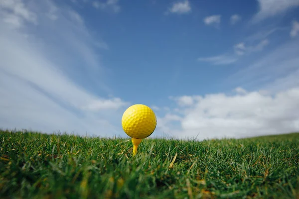 Κίτρινο Γκολφ Μπάλα Στο Τεε Πράσινο Γρασίδι Και Γαλάζιο Φόντο — Φωτογραφία Αρχείου