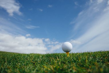 tee, yeşil çim ve mavi gökyüzü arka plan üzerinde Golf topu