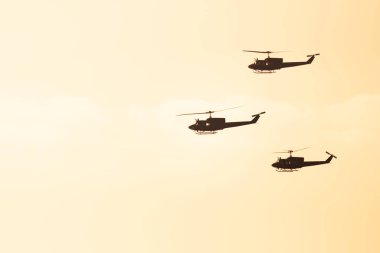 Üç helikopter güneş ışığı arka planda uçan