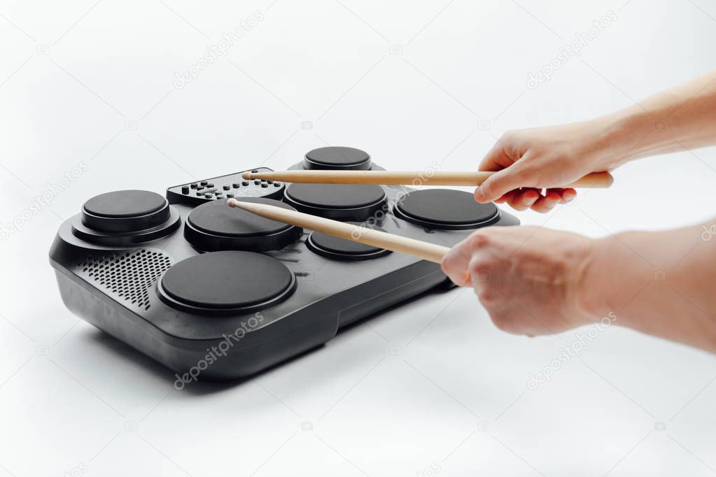 hands playing on portable electronic drums, white background