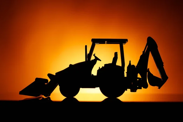 Backhoe trekker silhouet, oranje zonsondergang achtergrond — Stockfoto