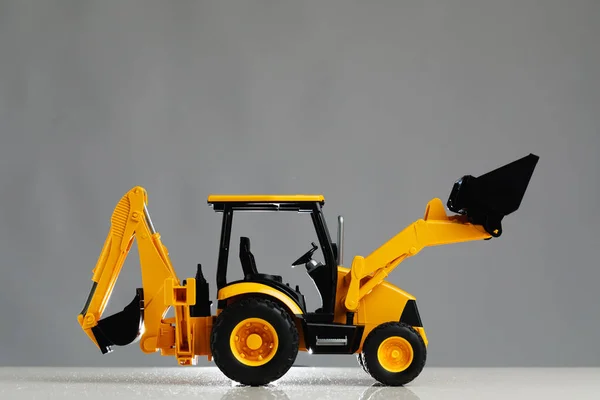 Backhoe traktor mainan, latar belakang abu-abu — Stok Foto