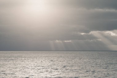 açık denizde güneş ışınları ile bulutlu gökyüzü