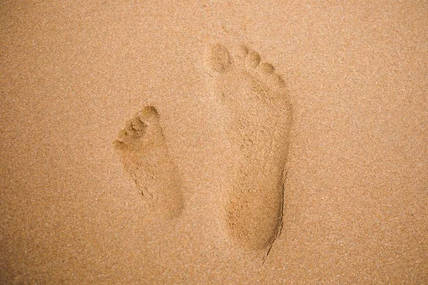 Pegadas de crianças e adultos na praia de areia — Fotografia de Stock