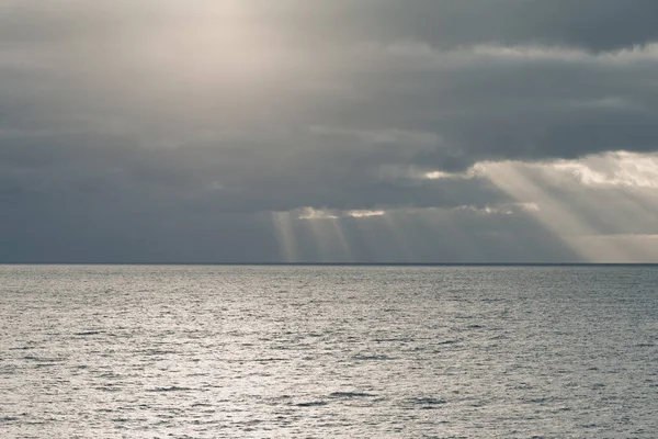 Bewolkte hemel met de stralen van de zon in de open zee — Stockfoto