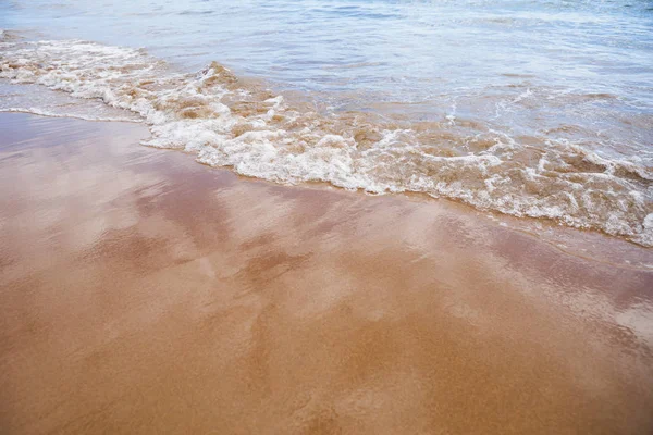 Våt sandstrand bakgrund och havet vatten — Stockfoto