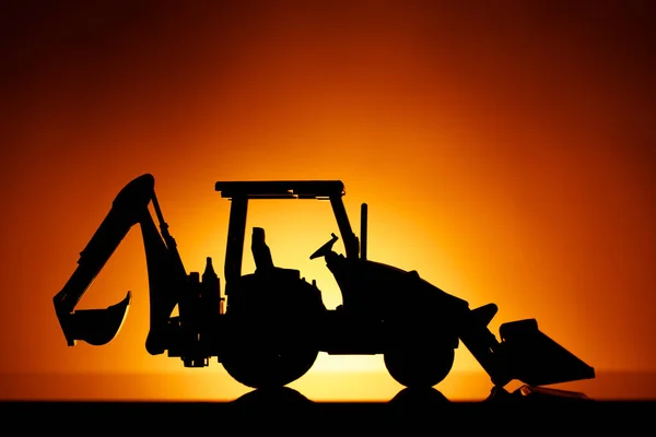 Backhoe trekker silhouet, oranje zonsondergang achtergrond — Stockfoto