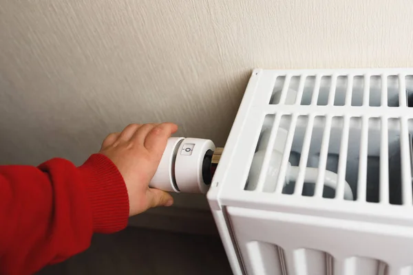 Child hand controls thermostatic knob of heating radiator — Stock Photo, Image