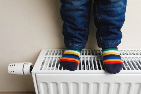 Criança pés com meias coloridas no radiador — Fotografia de Stock