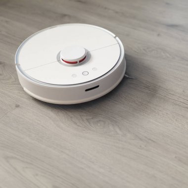 Plastik zeminde robotik elektrik süpürgesi çalışıyor.