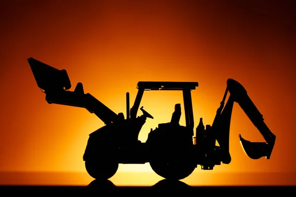 Backhoe tractor silhouette, orange sunset background — Stock Photo, Image