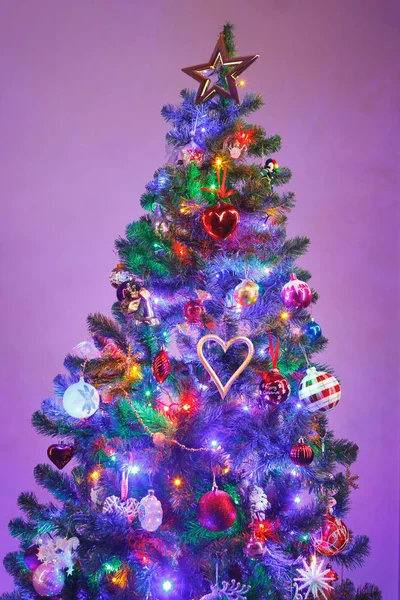 Kerstboom met multicolor LED-verlichting en paarse achtergrond — Stockfoto