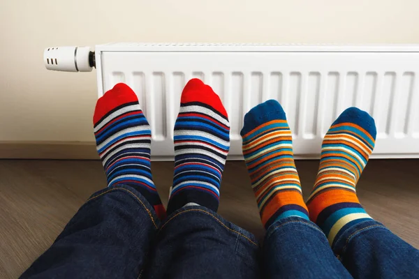 Legs with colorful socks in front of heating radiator — Stock Photo, Image