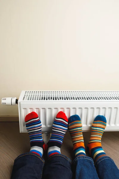 Pernas com meias coloridas na frente do radiador de aquecimento — Fotografia de Stock