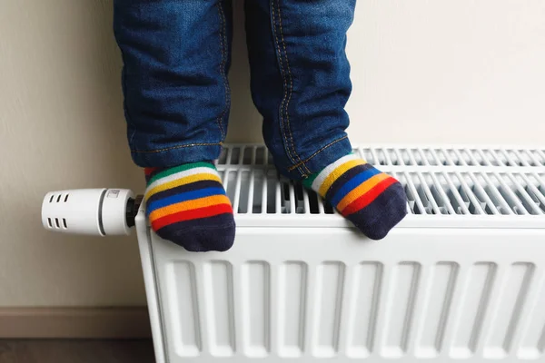 Kindervoeten met kleurrijke sokken op radiator — Stockfoto