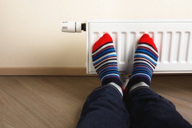 legs with colorful socks in front of heating radiator clipart