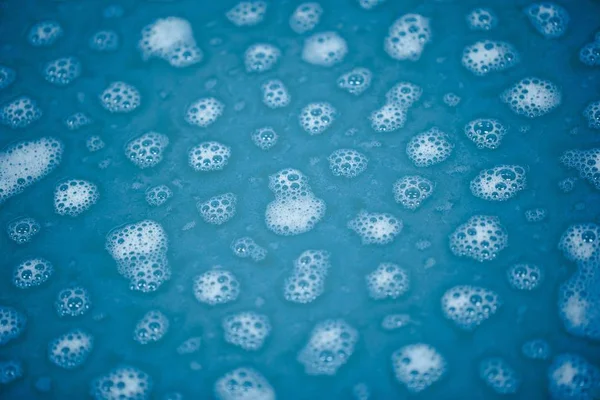 Manchas de espuma na água azul — Fotografia de Stock
