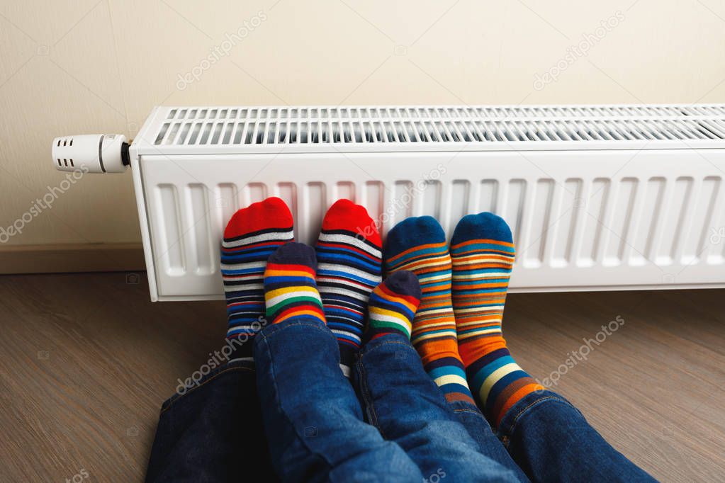 legs with colorful socks in front of heating radiator