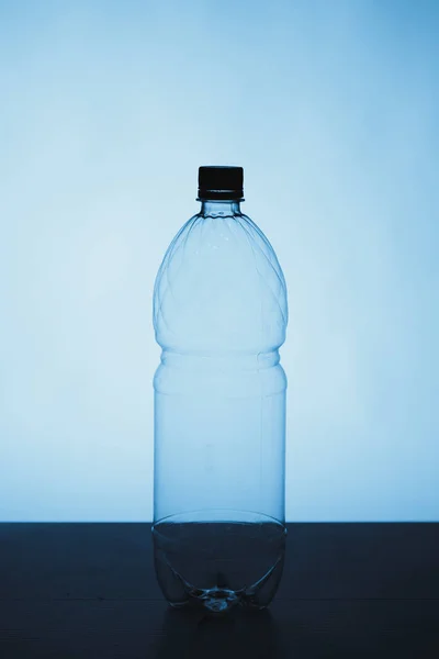 Pusta plastikowa butelka sylwetka na niebieskim tle — Zdjęcie stockowe