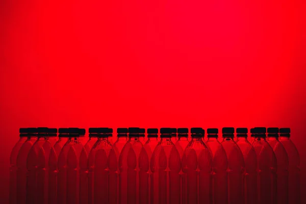 红色背景上的空塑料瓶剪影 — 图库照片