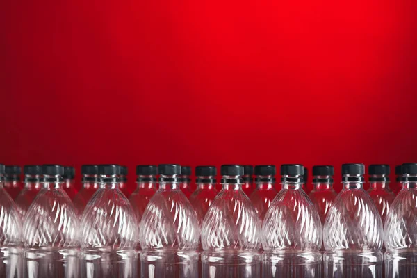 Kırmızı arka plan üzerinde boş plastik şişeler — Stok fotoğraf