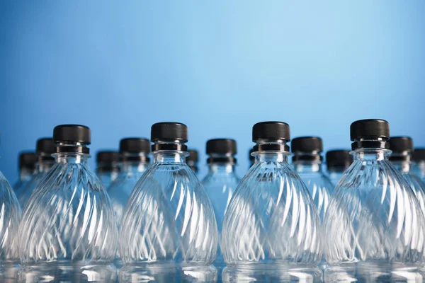 Mavi arka plan üzerinde boş plastik şişeler — Stok fotoğraf