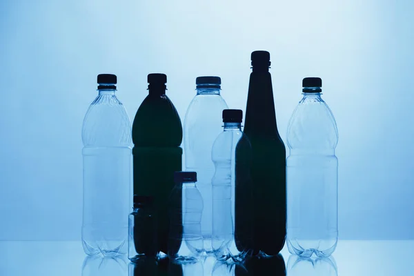 Silhuetas de garrafa de plástico vazias no fundo azul — Fotografia de Stock