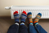 nohy s barevnou ponožkami před topným radiátorem