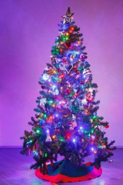 Çok renkli led ışıklar ve mor arka plan ile Noel ağacı