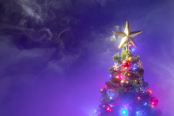 Árvore de Natal com luzes festivas, fundo roxo com fumaça — Fotografia de Stock