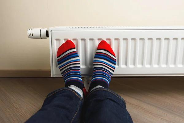 Beine mit bunten Socken vor Heizkörper — Stockfoto