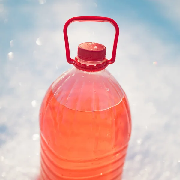 Fles met niet-bevriezing voorruit ruitensproeiervloeistof, sneeuw achtergrond — Stockfoto
