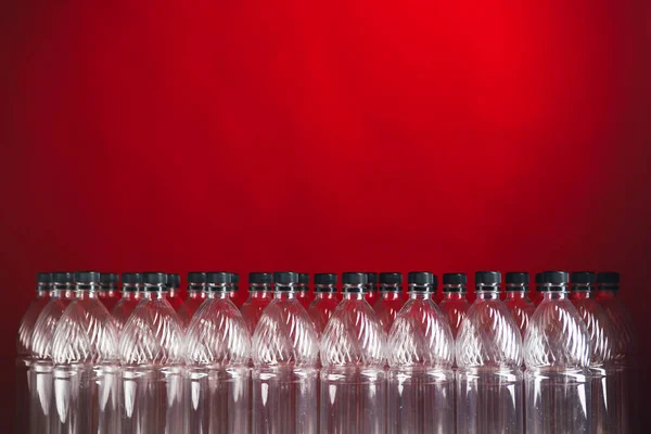 Lege plastic flessen op rode achtergrond — Stockfoto