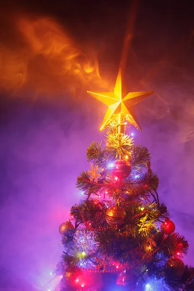 Χριστουγεννιάτικο δέντρο με εορταστικά φώτα, μωβ φόντο με καπνό — Φωτογραφία Αρχείου